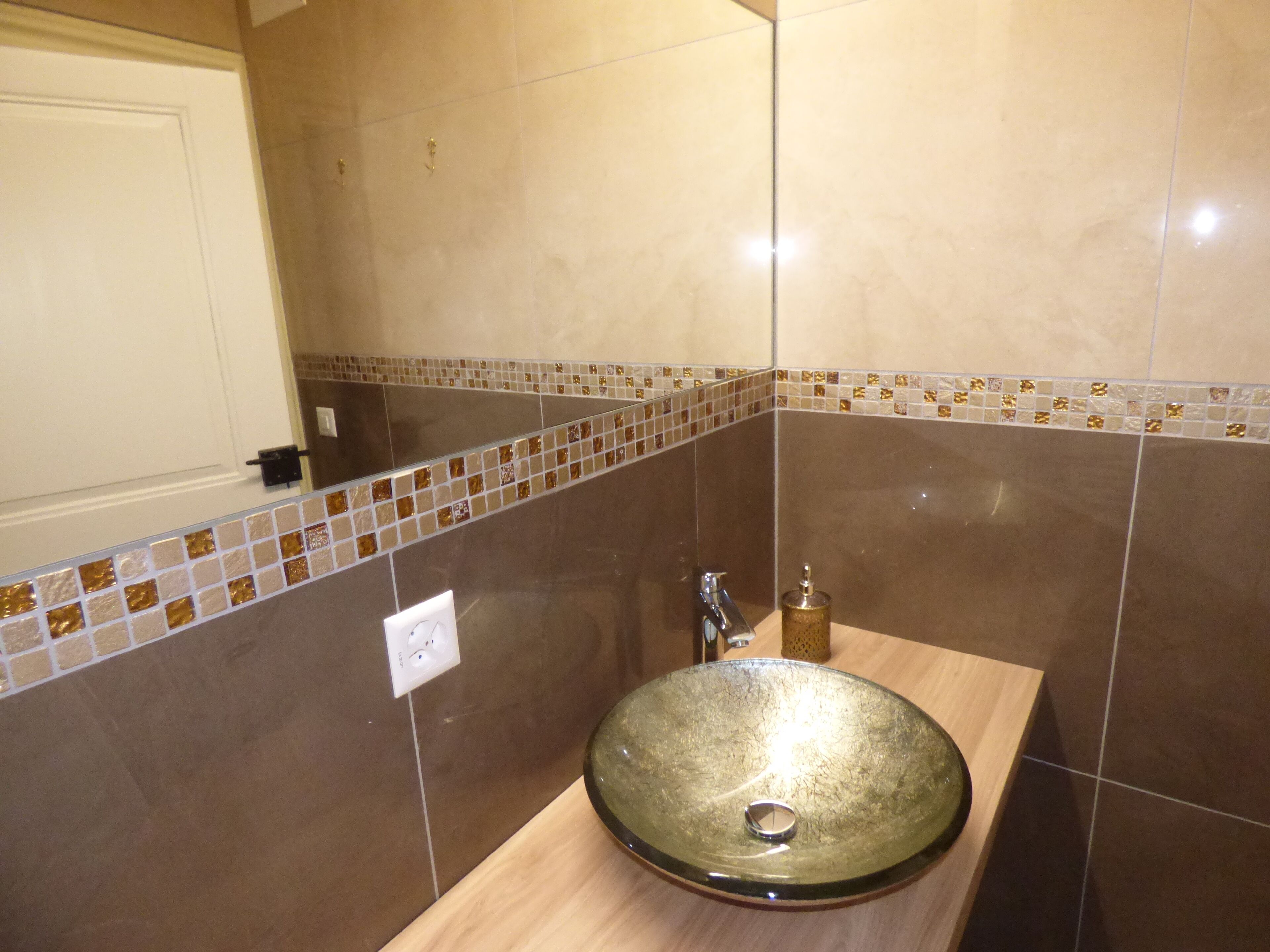 A bathroom with a glass sink, tiled walls, and a wooden countertop.