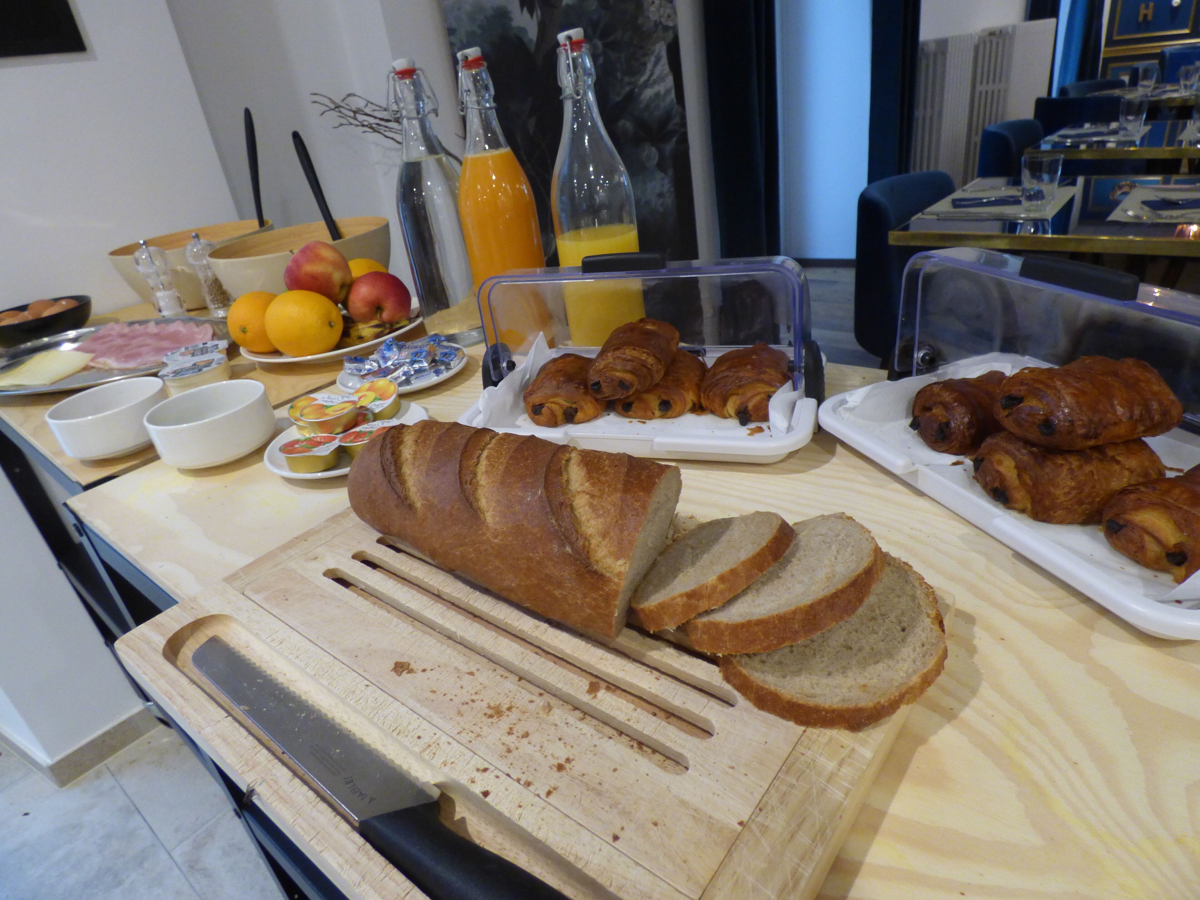 Een ontbijtbuffet met brood, gebak, fruit en sap.
