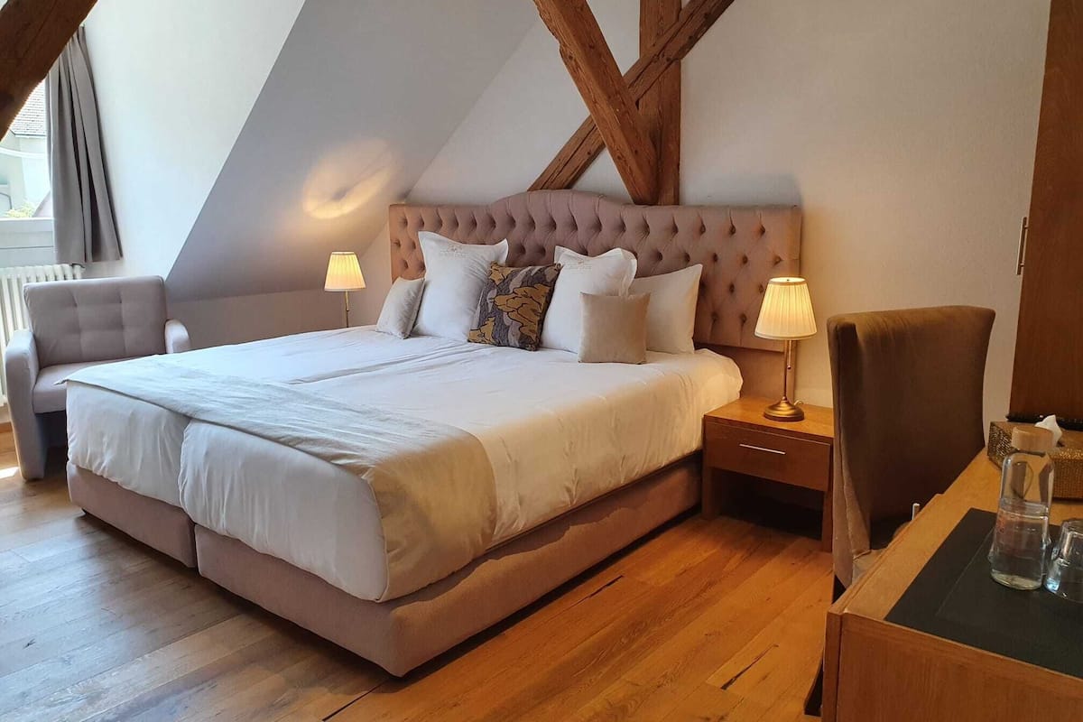 Une chambre avec un grand lit, deux tables de chevet, une chaise et une structure de plafond en bois.
