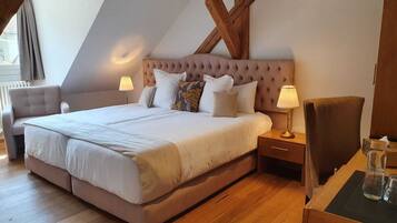 A bedroom with a large bed, two bedside tables, a chair, and a wooden ceiling structure.