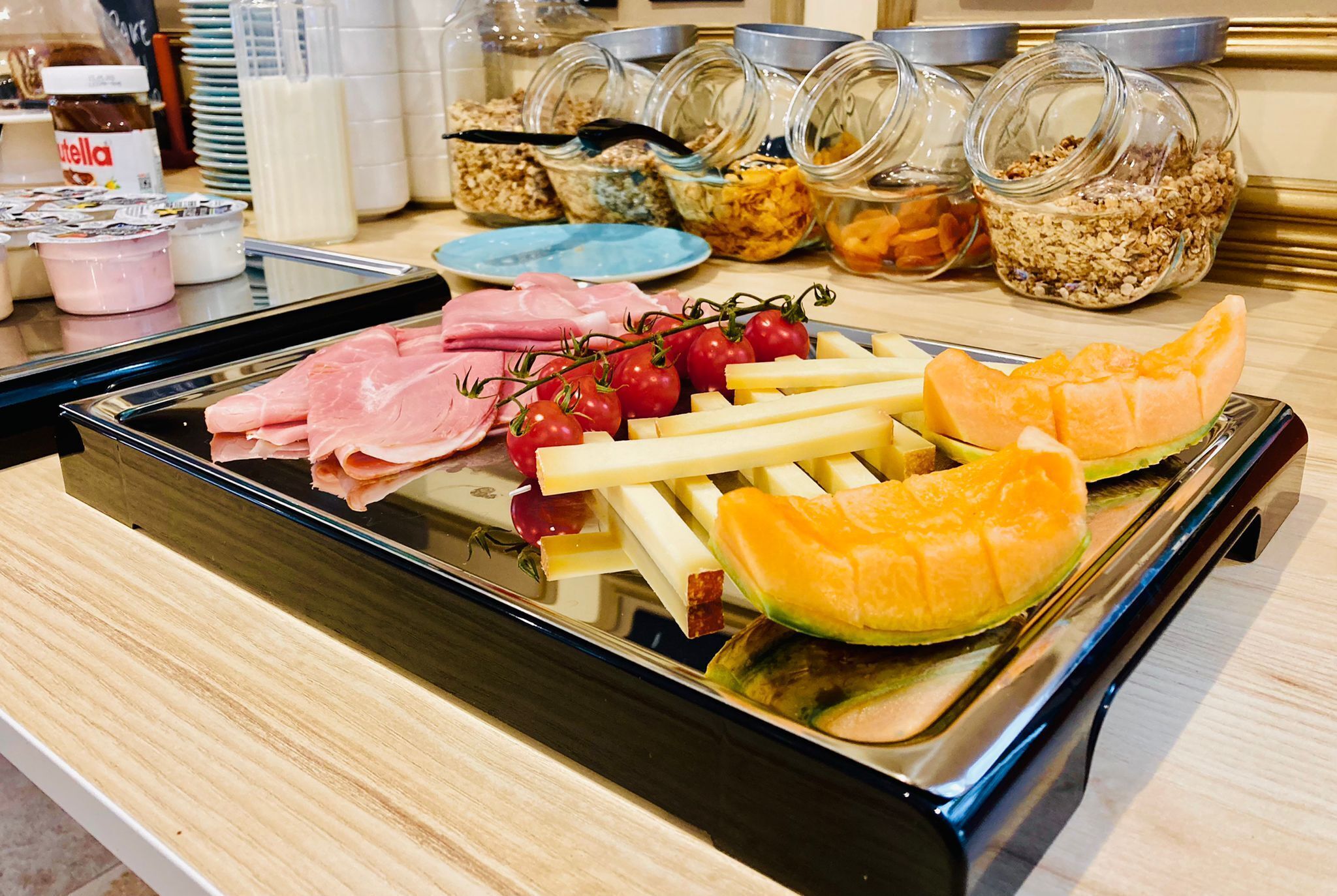 Un buffet proposant une variété d’aliments, notamment des viandes, des fromages, des fruits et des céréales.