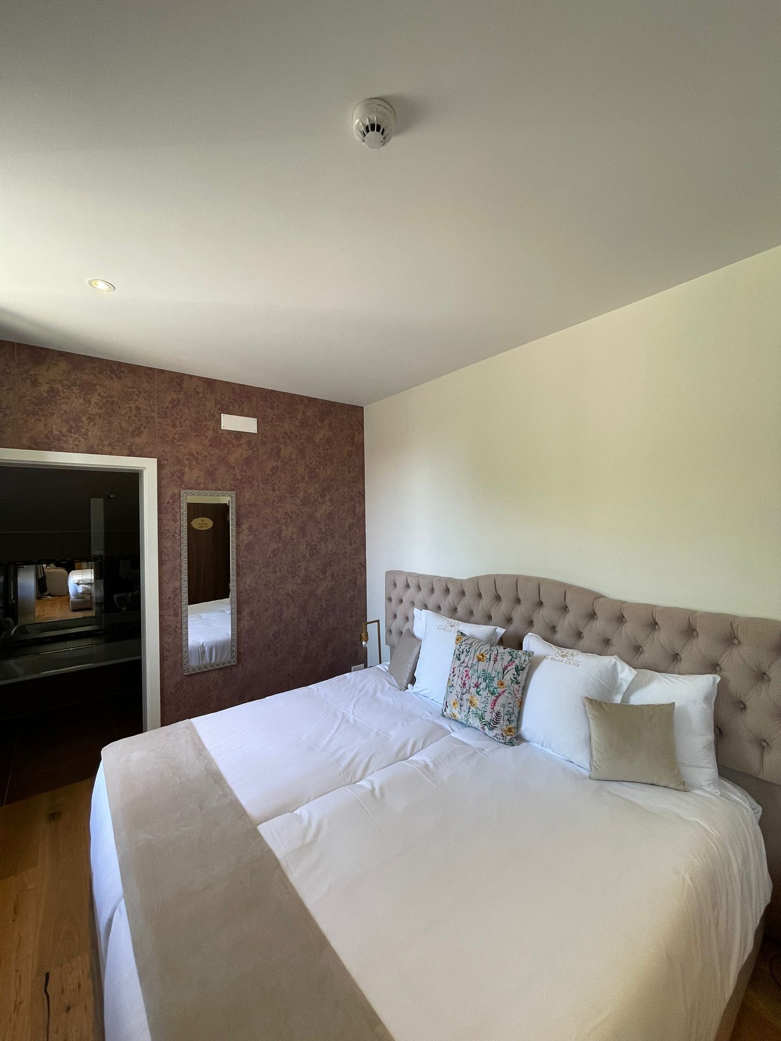 Une chambre d’hôtel avec un grand lit, un miroir et une porte donnant sur une salle de bain.