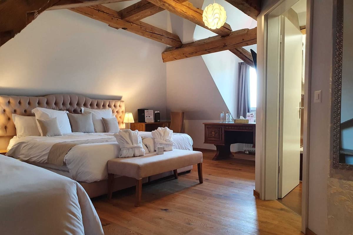 Une chambre avec un grand lit, un banc en bois et un bureau avec une lampe.