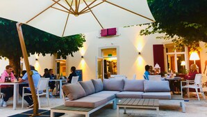 An outdoor seating area with a large umbrella, cushioned seating, and tables. - Hotel La Belle Croix (Romont)