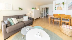 A modern living room with a sofa, coffee table, and dining area. - Georgina: Apartment with sea view and community pool (L'Escala)