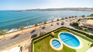A coastal view with a swimming pool, a road, and a beach. - Georgina: Apartment with sea view and community pool (L'Escala)