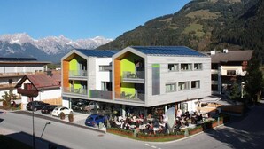 A modern building with a restaurant on the ground floor, featuring a mountain backdrop.