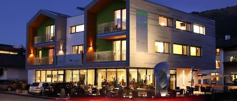 A modern hotel with a two-story structure, outdoor seating area, and a visible restaurant sign.