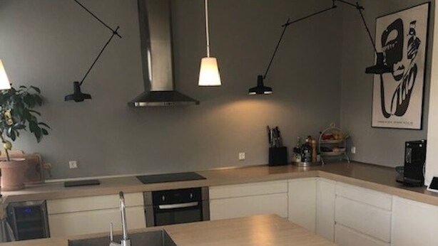 Una cucina moderna con isola centrale, mobili bianchi e illuminazione a sospensione.