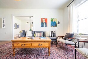 Ein Wohnzimmer mit Couch, Holz-Couchtisch, gestreiftem Sessel und einem gemusterten Teppich.