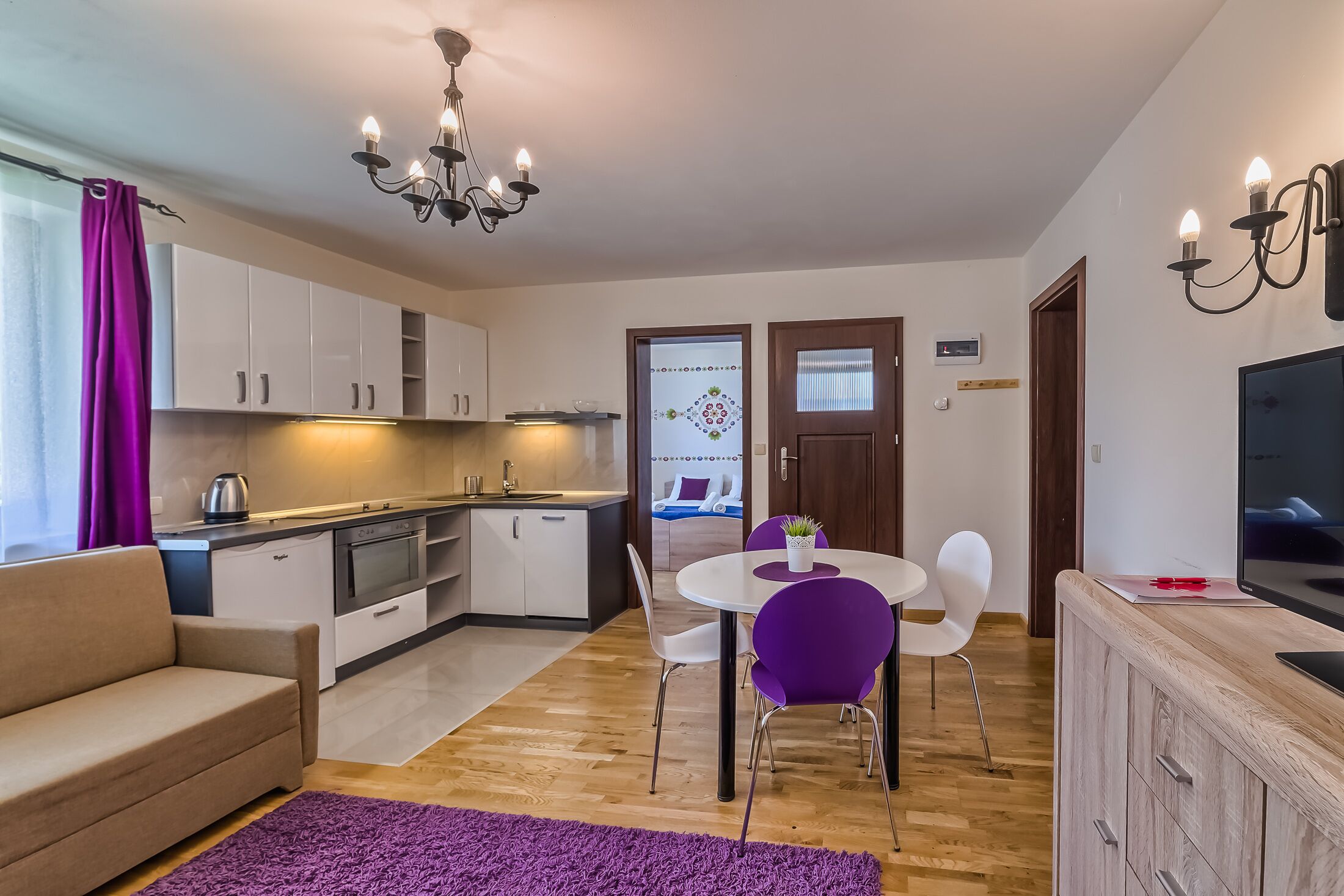 Un espacio habitable compacto con kitchenette, comedor y sofá.
