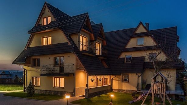 A two-story house with a balcony, a playhouse, and a well-lit driveway. - Aparthotel Delta Bialka (Bukowina Tatrzanska)