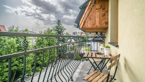 A balcony with a wooden table and chairs, a lantern, and a potted plant. - Aparthotel Delta Bialka (Bukowina Tatrzanska)