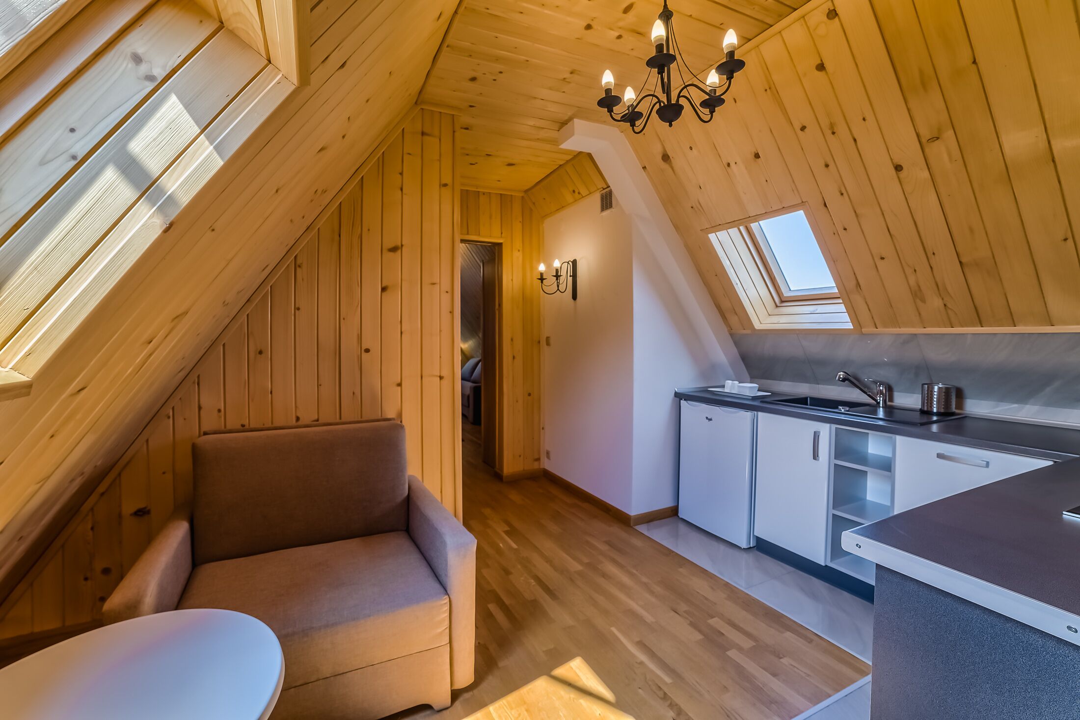 Une chambre confortable située dans les combles, avec un canapé, une petite table, un coin cuisine et une lucarne.