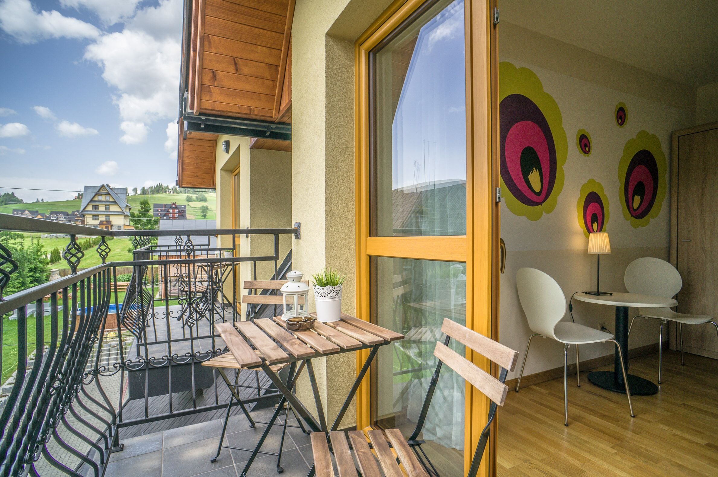 A balcony with wooden furniture, a potted plant, and a view of the countryside.