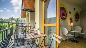 A balcony with wooden furniture, a potted plant, and a view of the countryside.