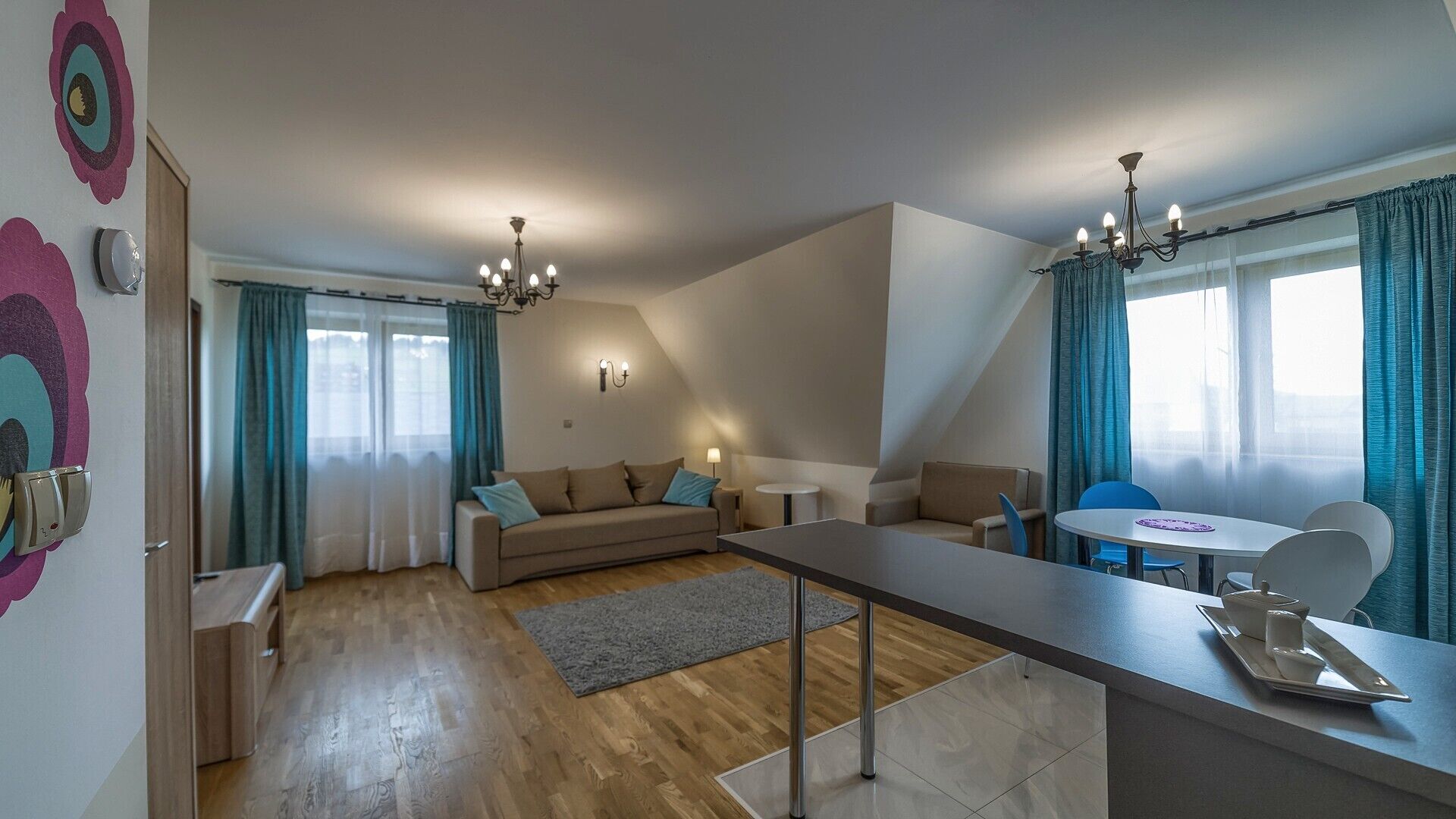 A modern living room with a sofa, a dining table, and a kitchen area.