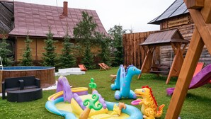 A backyard with a swimming pool, inflatable play area, and a wooden playhouse. - Aparthotel Delta Bialka (Bukowina Tatrzanska)