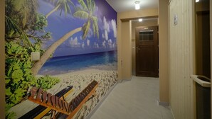 A hallway with a beach mural, a bench, and a door. - Aparthotel Delta Bialka (Bukowina Tatrzanska)