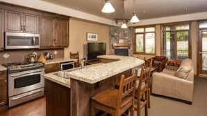 Una cocina amplia con encimeras de granito, electrodomésticos de acero inoxidable y chimenea de piedra.