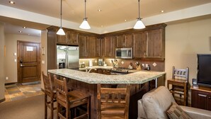 Una cocina amplia con armarios de madera, una isla con encimera de granito y electrodomésticos modernos.