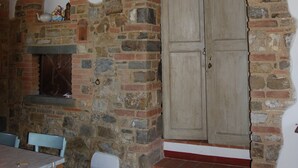Eine rustikale Steinmauer mit einer Holztür und Stufen, die zu einer Erschließung hinaufführen.