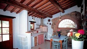 Eine rustikale Küche mit Steinwand, Holzbalken und einem großen Fenster.