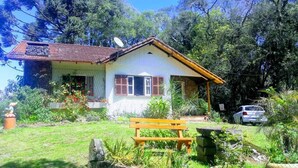 A house with a garden, a bench, and a car parked outside. - Pousada Heritage Colonial (Nova Petropolis)