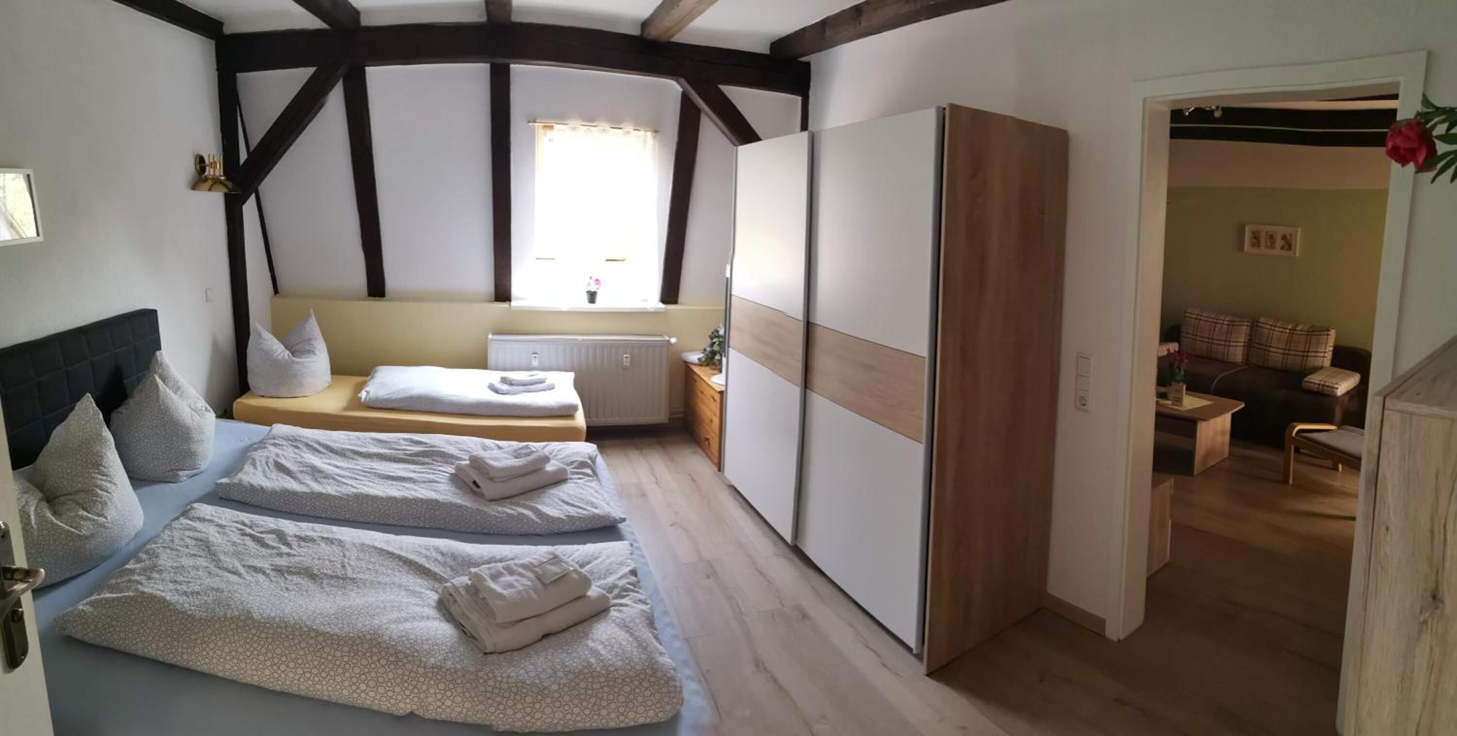Un dormitorio con cama, mesitas de noche, una ventana y vistas a otra habitación.