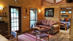 Ein gemütliches Blockhaus-Interieur mit Holzvertäfelung, einer Couch, einem Couchtisch und einem Essbereich.