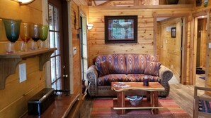 Ein gemütliches Holzinterieur mit einem gemusterten Sofa, einem Holztisch und einer Ablage mit bunten Gläsern.