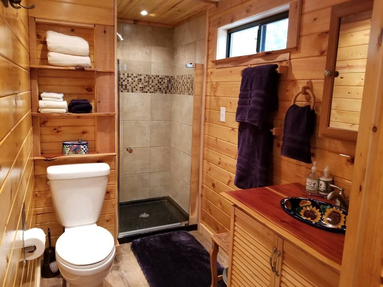 Un baño de madera con ducha, inodoro y lavamanos.