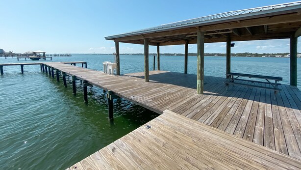 A wooden pier extending into calm water, with a covered seating area and a bench. - TWO POOLS, FISHING PIER, PRIVATE BEACH ACCESS, COZY ACCOMMODATIONS (Gulf Shores)