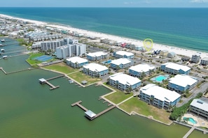 An aerial view of a coastal hotel area with buildings, a beach, and a marina.
