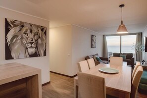 Relax in a serene space with a comfortable seating area, dining table for four, and a stunning sea view.