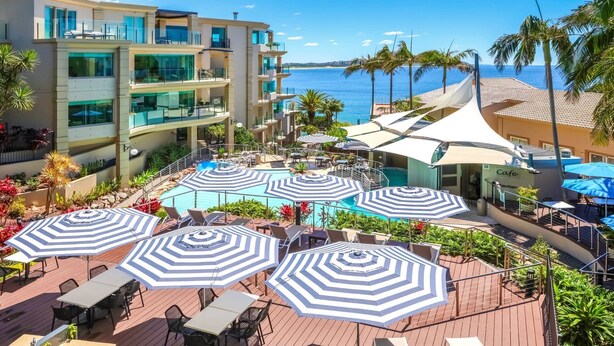 A resort with a pool area, outdoor seating, and a view of the ocean.
