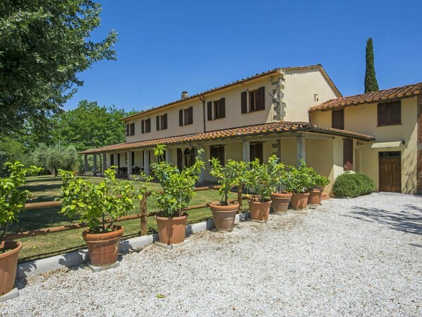 A two-story building with a covered patio area and a gravel driveway.