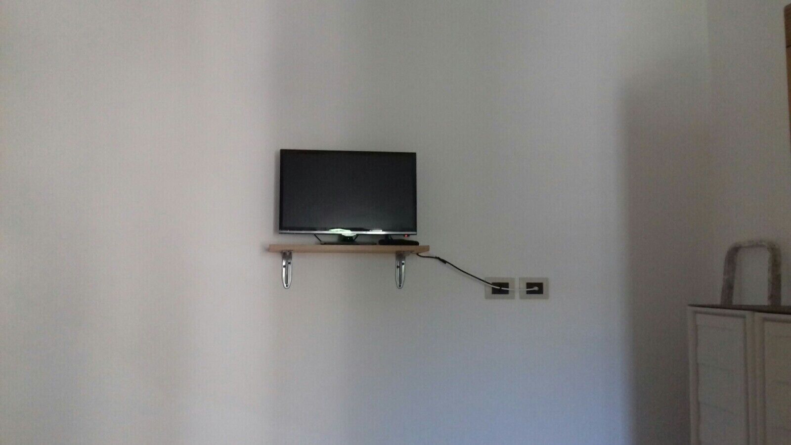 Ein an der Wand befestigter Fernseher mit Kabelanschluss an einer Steckdose.
