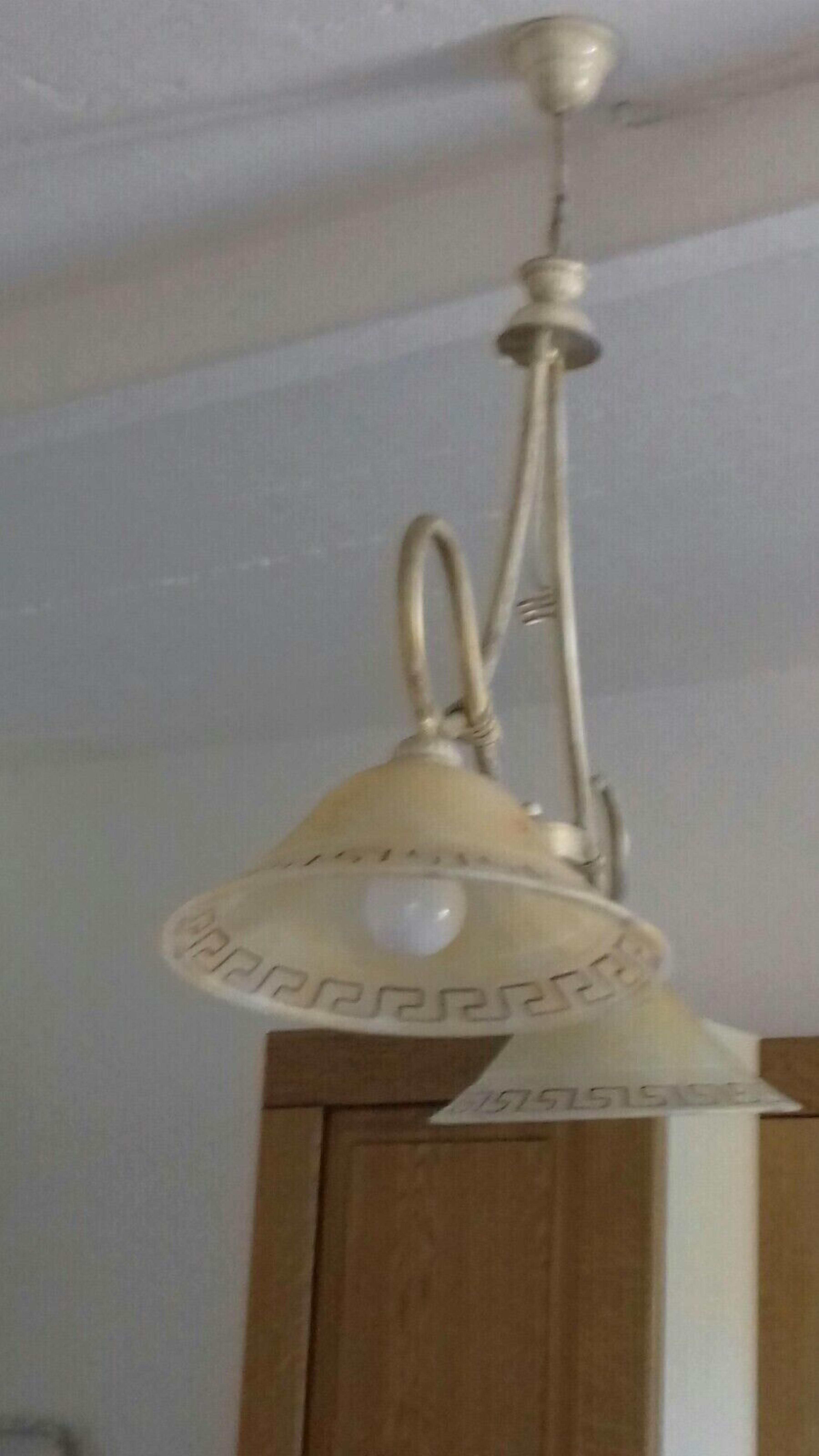 Een plafondlamp met een witte kap en zichtbare lamp.