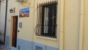 A building with a window featuring black metal bars, a door, and a sign advertising breakfast. - B&B Gerace (Badolato)
