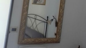 A room with a bed, a bedside table, a wall-mounted air conditioner, and a framed mirror with a picture. - B&B Gerace (Badolato)