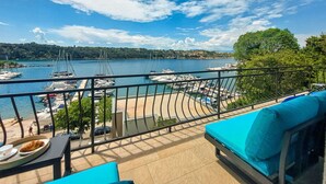 A balcony with a view of a marina, a dining table with a plate of food, and a blue cushioned bench. - Lovely apartment for 5 guests with WIFI, A/C, TV, balcony and pets allowed (Rijeka)