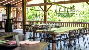 Ein Essbereich im Freien mit einer Holzterrasse, Metallstühlen und einem Tisch für vier Personen.