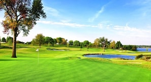 Un parcours de golf avec un drapeau, des arbres et un plan d’eau.