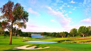 Un parcours de golf avec des bunkers de sable, un obstacle d’eau et un mât de drapeau.