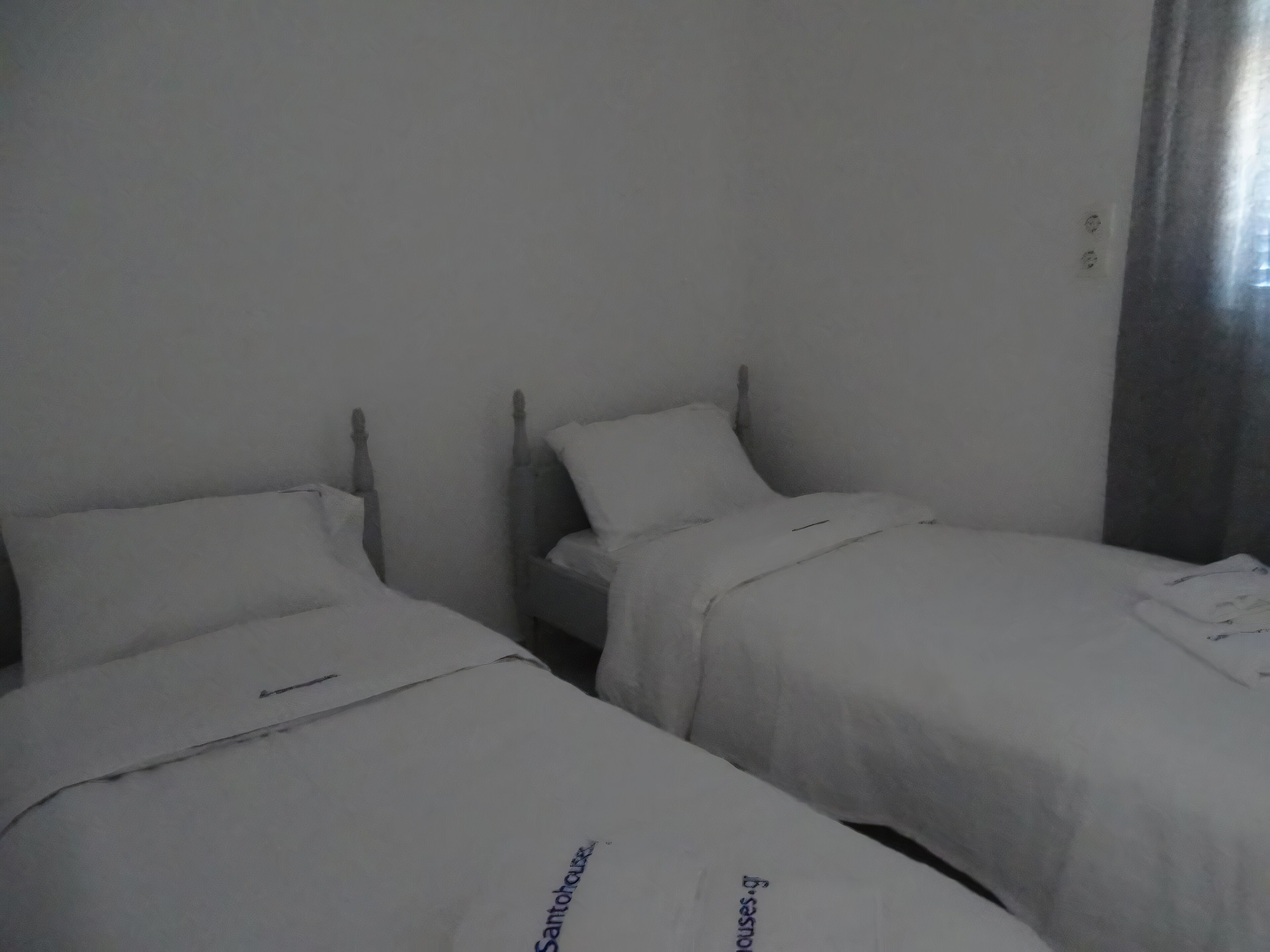 A room with two single beds, each with a white bedspread and a pillow.