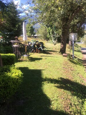 Un jardín con mobiliario exterior, una mesa y sillas.