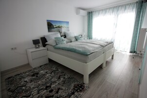 Un dormitorio moderno con una cama grande, mesitas de noche, una alfombra y un cuadro en la pared.
