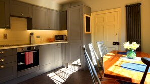 A modern kitchen with grey cabinets, a microwave, and a toaster. There is a dining table with chairs and a vase of flowers. - 14 St Saviours Place, YORK (York)
