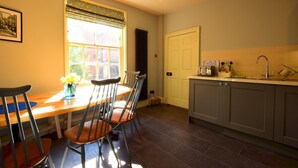 A kitchen with a dining table and chairs, a window with curtains, and a sink with a faucet. - 14 St Saviours Place, YORK (York)